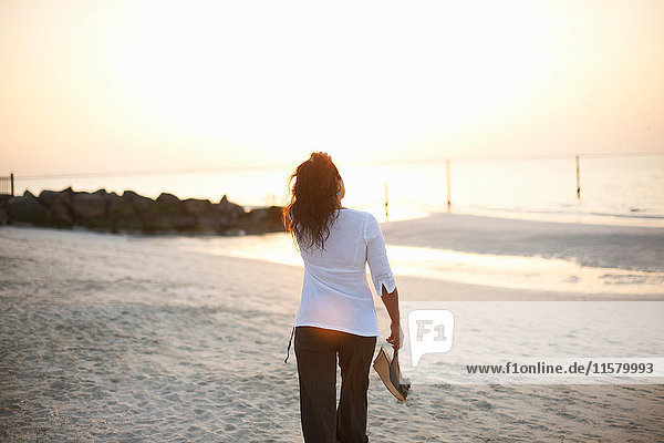 Rückansicht einer Frau  die am Strand spazieren geht  Dubai  Vereinigte Arabische Emirate