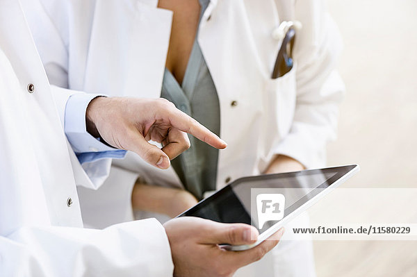 Zwei Ärzte betrachten ein digitales Tablett  mittlerer Abschnitt  Nahaufnahme
