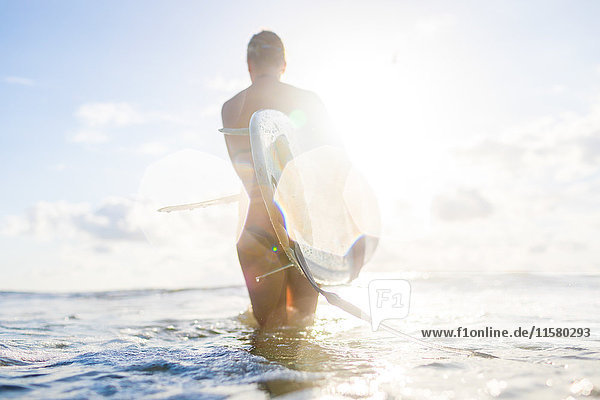 Rückansicht einer Frau mit Surfbrett im sonnenbeschienenen Meer  Nosara  Provinz Guanacaste  Costa Rica