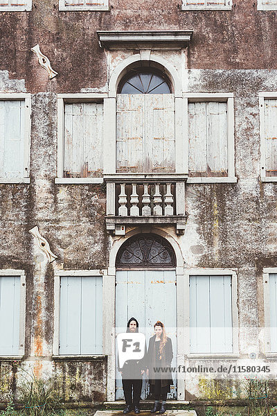 Portrait of couple standing at doorway of old house