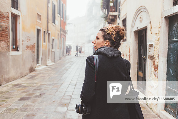 Junge Frau mit Kamera  die ihr auf der Straße über die Schulter schaut  Venedig  Italien