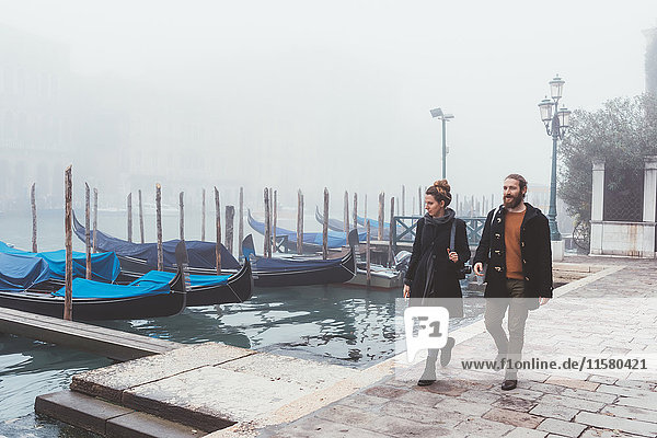 Couple strolling along misty canal waterfront  Venice  Italy
