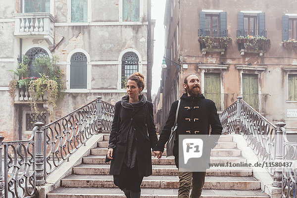 Couple holding hands and moving down stairway  Venice  Italy