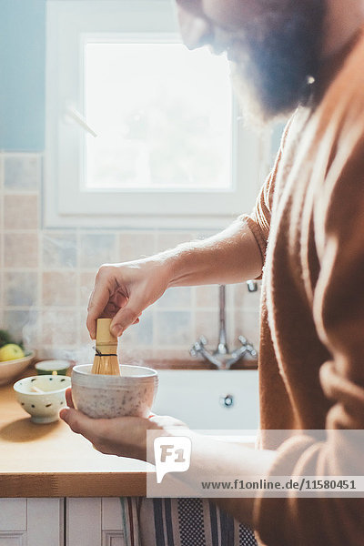 Cropped shot of man stirring bowl in kitchen
