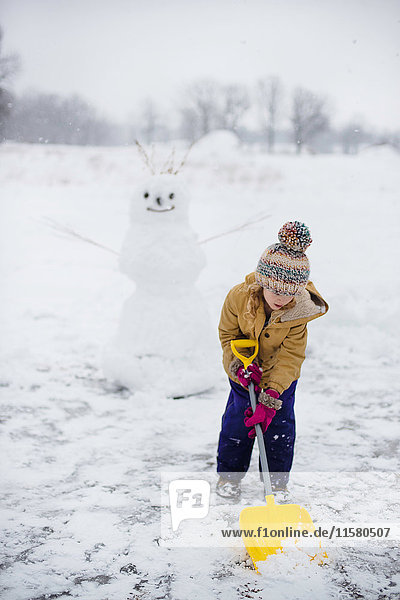 Mädchen schaufelt Schnee vor dem Schneemann  Lakefield  Ontario  Kanada