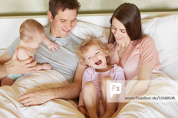 Female toddler and baby sister in bed with parents