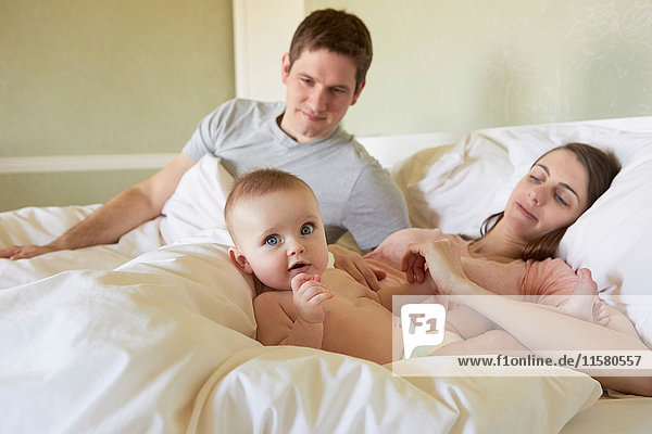 Portrait of baby girl lying on bed with parents