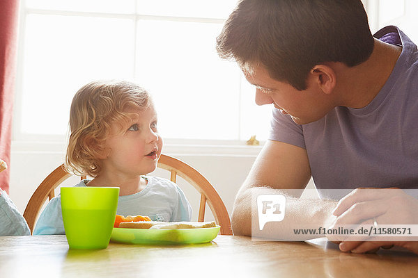 Mid adult man and toddler daughter at kitchen table