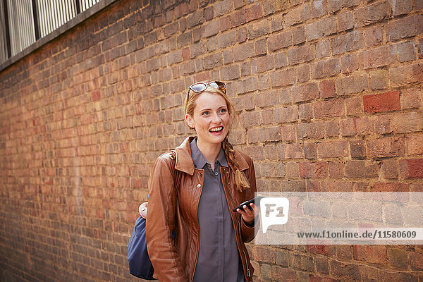 Woman walking along brick wall  London  UK