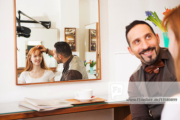 Friseur berät Kunden über Frisur im Salon