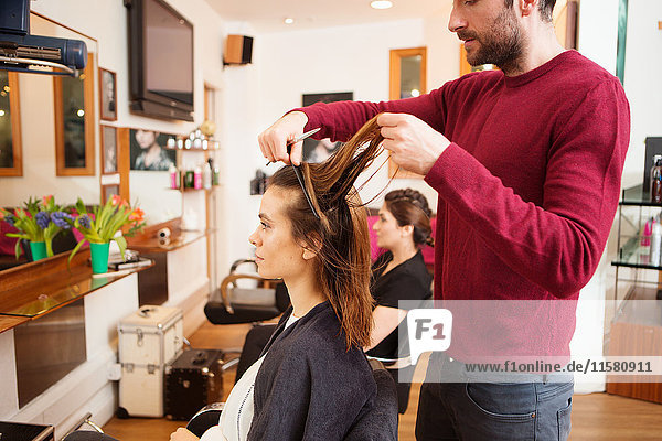Female customer having long brown hair trimmed in hair salon