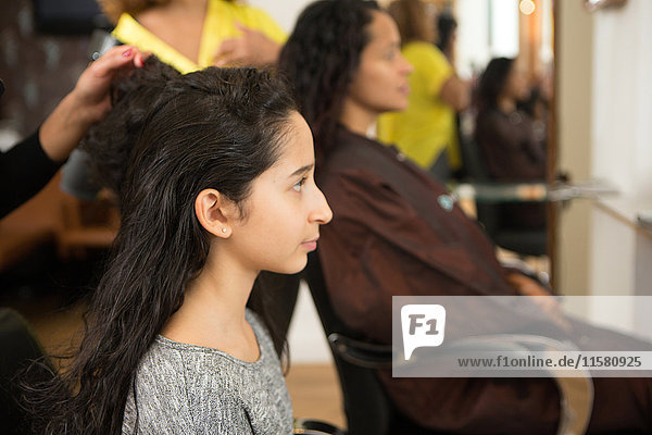 Girl and mother having their hair styled in hair salon