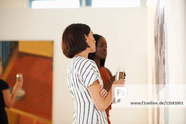 Zwei Frauen betrachten Ölgemälde bei der Eröffnung einer Kunstgalerie