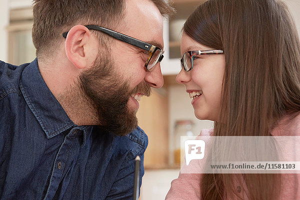 Mittelgroßer erwachsener Mann und Tochter lächeln von Angesicht zu Angesicht