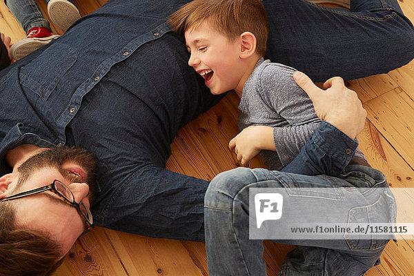 Overhead view of boy and father laughing on floor