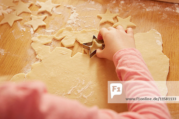 Over shoulder cropped view of girl making star shape pastry at kitchen table