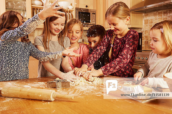 Boy and girls fooling around while baking at kitchen table