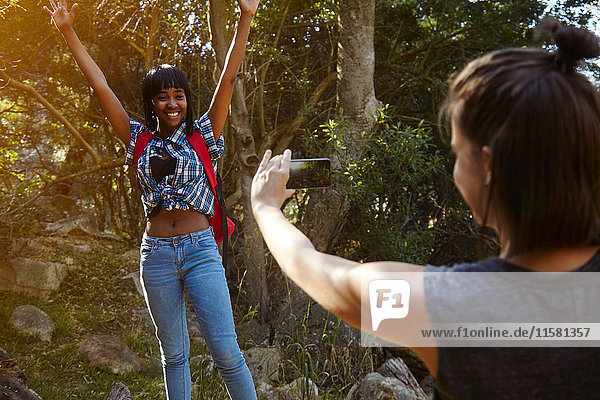Two friends hiking  young woman taking photograph of friend  using smartphone  Cape Town  South Africa