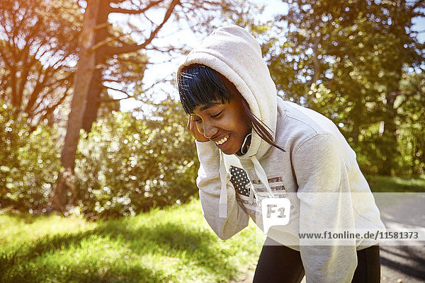 Junge Frau in ländlicher Umgebung  trägt Kapuzen-Sweatshirt   lächelt