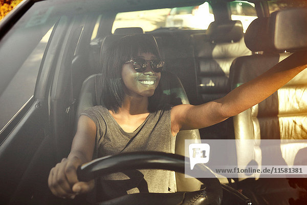 Junge Frau beim Einstellen des Rückspiegels im Auto  Blick durch das Autofenster