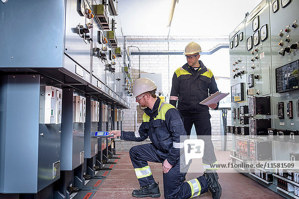 Workers testing for noise in electricity substation