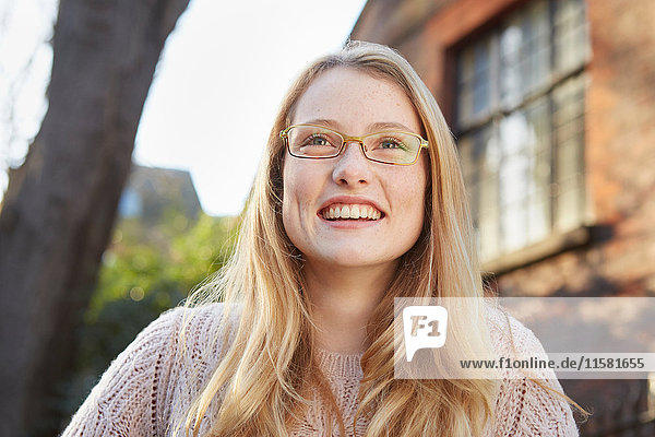 Porträt einer jungen Frau im Freien  lange blonde Haare und Brille