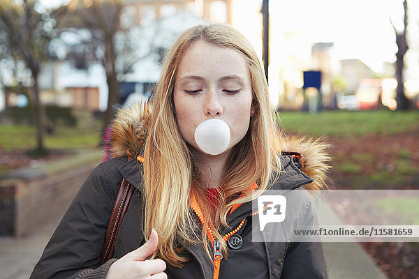 Porträt einer jungen Frau  im Freien  Blasen mit Bubblegum