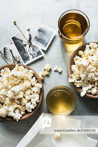 Still life of popcorn and drink  beside old black and white photographs  overhead view