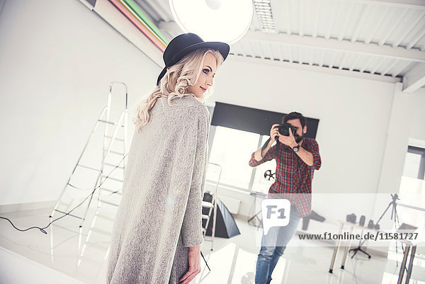 Männlicher Fotograf fotografiert weibliches Modell auf studio-weißem Hintergrund