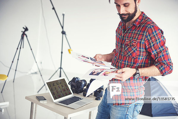 Male photographer looking at photographs from photo shoot in studio