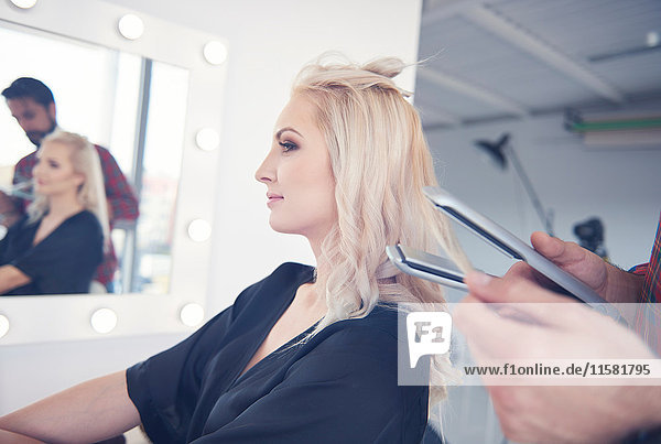 Hände eines Friseurs  der Haarglätter für ein Model beim Fotoshooting hält