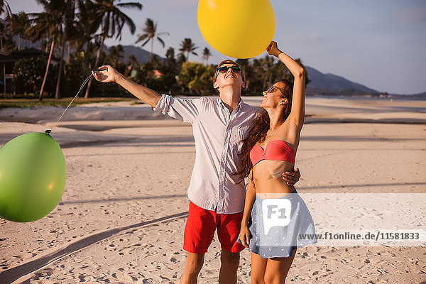 Junges Paar am Strand beim Aufblicken auf Luftballons  Koh Samui  Thailand