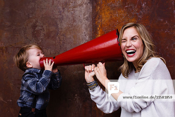 Young boy speaking into megaphone  woman holding megaphone to her ear
