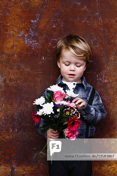 Young boy holding bunch of flowers