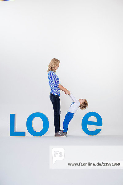 Mother and son holding hands  standing between three-dimensional letters  creating the word LOVE