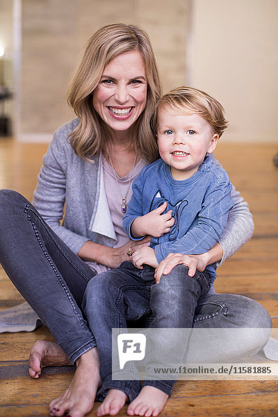 Portrait of mother and son  sitting on floor  smiling