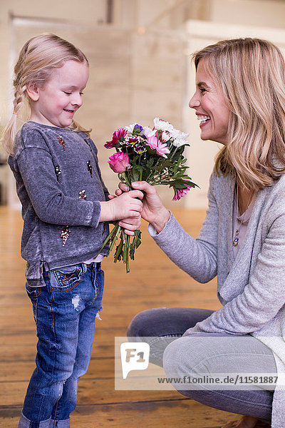 Young girl giving mother bunch of flowers