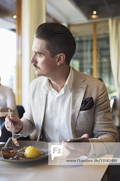 Businessman using mobile phone while looking away at restaurant