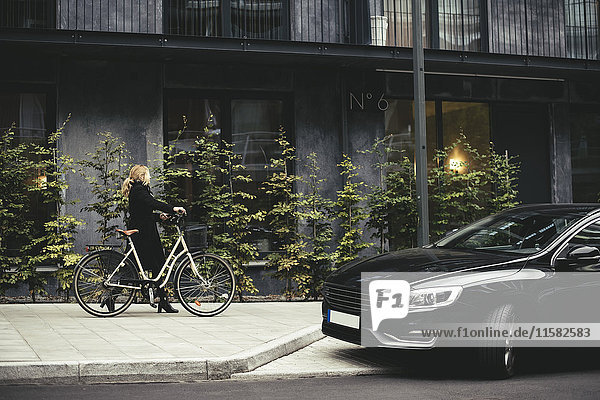 Durchgehende Seitenansicht der Geschäftsfrau mit Fahrradspaziergang am Gebäude