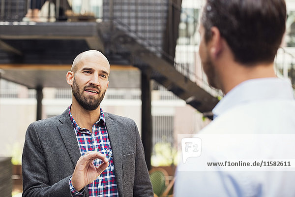 Confident businessman discussing with male colleague at office yard
