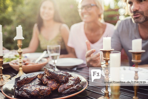 Couple and female friend sitting at dining table during garden party in back yard