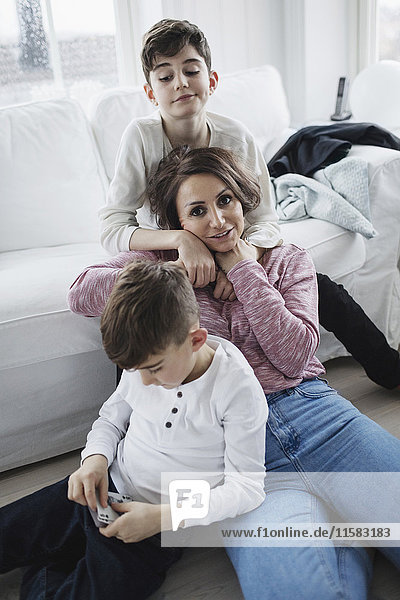 Porträt einer Frau mit Söhnen im Wohnzimmer zu Hause