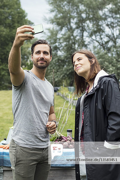 Mittleres erwachsenes Paar nimmt Selfie durch Handy im Stadtgarten mit.