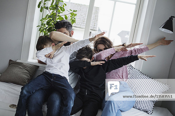 Fröhliche Familie beim Tupfen auf dem Sofa im Wohnzimmer zu Hause