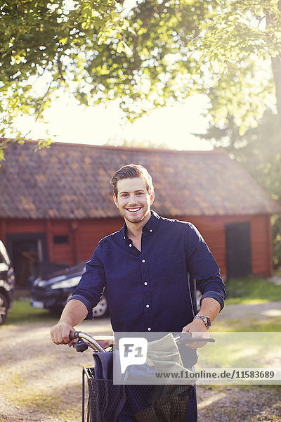 Portrait of smiling man with bicycle at backyard