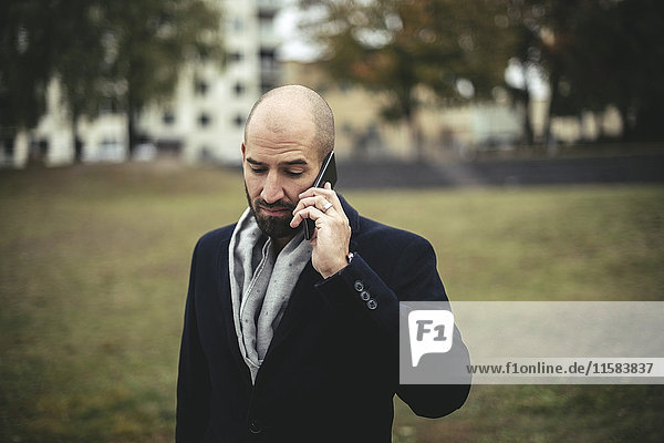 Mid adult businessman talking on mobile phone in park