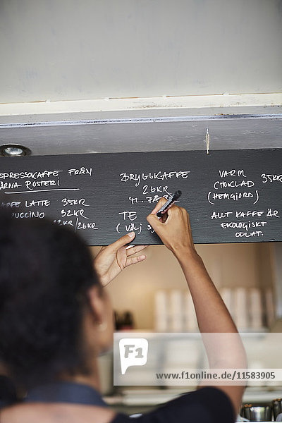 Rückansicht der Kellnerin beim Schreiben des Menüs im Cafe