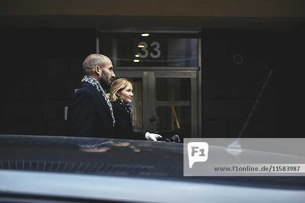 Seitenansicht eines Geschäftsmannes und einer Geschäftsfrau,  die am Gebäude vorbeigehen.