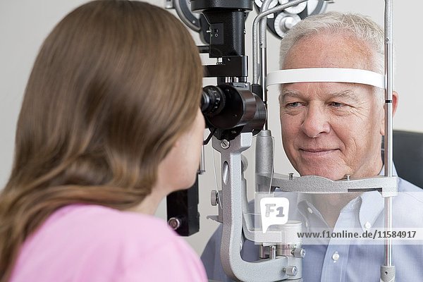 Female optician testing senior man's eyesight.