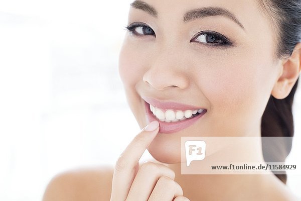 MODEL RELEASED. Young Asian woman touching lip  portrait.